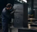 A Loxmet technician checks drawer alignment and the key lock on a lockable filing cabinet during factory quality control for secure office document storage