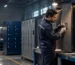 A technician compares locker lock types on a metal locker production line before staff units are installed at a managed workplace